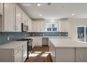 Bright kitchen featuring an island, white cabinets, stainless steel appliances, and wood-look flooring at 8703 Forte Dr, North Charleston, SC 29406