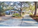 Charming brick home featuring a welcoming front porch and beautifully landscaped yard with mature trees at 10812 Dorchester Rd, Summerville, SC 29485