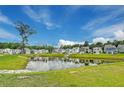 Scenic view of a pond reflecting the sky, surrounded by well-kept homes and green lawns at 131 Brant Dr, Summerville, SC 29483