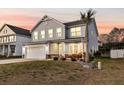 Inviting two-story home at dusk, featuring a lush lawn and warm interior lighting at 134 Country Oaks Ln, Wando, SC 29492
