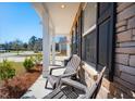 Inviting front porch featuring comfortable Adirondack chairs, perfect for enjoying the outdoors, with stone accents at 2916 Cavalcade Cir, Johns Island, SC 29455