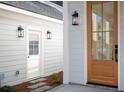 A craftsman style front door is framed by sleek black lanterns and light grey siding at 3285 Johnstowne St, Johns Island, SC 29455