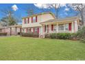 View of a home with a well-maintained lawn, red shutters, a portico, and inviting front porch at 7659 Allwood Ave, North Charleston, SC 29418