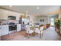 Open-concept kitchen, dining, and living room with hardwood floors and stainless steel appliances at 8018 Rackham Rd, Hollywood, SC 29470
