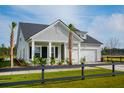 Inviting home exterior with black fence, manicured lawn and elegant landscaping with young palm trees at 1047 Tea Time Dr, Summerville, SC 29485