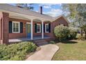 Close-up of brick home featuring the front porch, blue front door, shutters, and landscaped walkway at 107 Minus St, Saint George, SC 29477