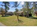A charming brick home is nestled among mature trees with a lush front yard, showcasing its inviting curb appeal at 107 Minus St, Saint George, SC 29477