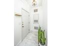 Well-lit entryway with light tile floors, featuring a coat rack and plant, creating a neat and inviting first impression at 1325 Telfair Way, Charleston, SC 29412