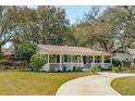 Charming home with front porch, landscaped yard, and winding driveway through mature trees at 1515 Devons St, Charleston, SC 29412