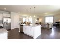 Bright kitchen featuring white cabinets, a large island with granite countertops, and stainless steel appliances at 182 E Pinckney St, Lincolnville, SC 29485