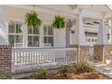 Inviting front porch with hanging plants, brick supports, and classic white railings at 233 Ashmont Dr, Wando, SC 29492