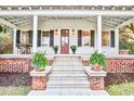 Close up of front porch with elegant white columns, brick accents, plants, and striking wood door at 8115 Adams Run School Rd, Adams Run, SC 29426