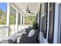 Relaxing covered porch featuring comfortable seating, ceiling fan, and views of the lush surrounding landscape at 112 Carpenter St, Summerville, SC 29486