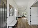Bright entryway with wood floors, a white bench, and a view into the living room with abundant natural light at 3215 Safe Harbor Way, Charleston, SC 29414