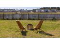 Backyard with a fire pit, wooden chairs, and a fenced yard overlooking the serene pond at 538 Spanish Wells Rd, Summerville, SC 29486