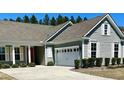 Charming single-story home boasts a well-manicured lawn, light gray siding and attached garage at 572 Tidewater Chase Ln, Summerville, SC 29486