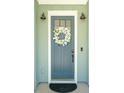 Close-up of a charming blue front door with a decorative floral wreath, and modern lighting at 1028 Harriman Ln, Charleston, SC 29492