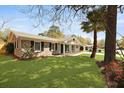 A single-story home showcasing a brick exterior, well-kept lawn and a large tree providing shade on a sunny day at 121 Milton Dr, Goose Creek, SC 29445