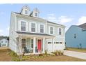 Charming two-story home with a bright red door and dormer windows at 1420 Homecoming Blvd, Ravenel, SC 29470