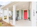 Inviting front porch with rocking chairs and a bright red front door at 1420 Homecoming Blvd, Ravenel, SC 29470