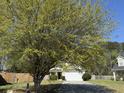 Exterior view of a well-manicured front yard with a mature tree shading a two-story home with an attached garage at 148 Saint Charles Way, Goose Creek, SC 29445