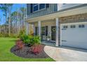 Inviting front porch with decorative plants, rocking chairs, and stone accents on a two-story home at 204 Torslanda Ln, Summerville, SC 29486