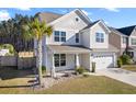 Charming two-story home showcasing a well-manicured lawn and an inviting covered porch at 211 Saxony Loop, Summerville, SC 29486