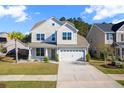 Charming two-story home showcasing a well-manicured lawn and attached two-car garage at 211 Saxony Loop, Summerville, SC 29486