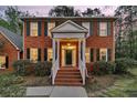Inviting brick home entrance with white columned porch, manicured bushes and brick steps at 235 Scalybark Rd, Summerville, SC 29485
