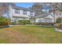 Two-story home with blue shutters, lush lawn, and landscaped garden beds create inviting curb appeal at 303 Axeminster Ct, Goose Creek, SC 29445