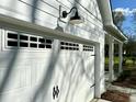 Close-up view of a garage door showcasing carriage-style detailing, decorative hardware, and a modern exterior light fixture at 312 Woodland Shores Rd, Charleston, SC 29412