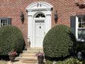 Elegant front door featuring a decorative archway, vintage sconces, and lush, manicured landscaping at 4 Chadwick Dr, Charleston, SC 29407