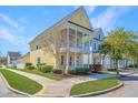 A bright yellow two-story home with double porches nestled in a quaint neighborhood at 401 Forsythia Ave, Summerville, SC 29483