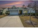 Charming home featuring a two-car garage, well-manicured lawn, and cozy front porch, basking in a colorful sunset at 415 Four Seasons Blvd, Summerville, SC 29486