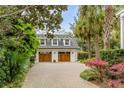 Detached two-car garage with wooden doors and brick driveway, surrounded by lush greenery at 7 Guerard Rd, Charleston, SC 29407