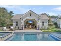 Relaxing pool house featuring an outdoor fireplace, TV, and comfortable seating near the pool at 7858 Gull Bay Dr, Awendaw, SC 29429
