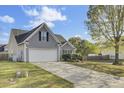 Side view of a house with a two-car garage, featuring an extended driveway, healthy lawn, and mature tree at 136 Rosario Dr, Summerville, SC 29483