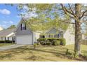 View of home with grey siding, a two-car garage, and beautiful mature trees and bushes at 136 Rosario Dr, Summerville, SC 29483