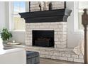 Close up shot of the brick fireplace with a black mantel and hearth, adding character and charm to the living space at 158 Woodland Oak Way, Summerville, SC 29485