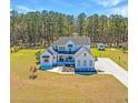 An impressive white farmhouse with lush green lawn, and a backdrop of tall trees on a sunny day at 161 Ryefield Ln, Ridgeville, SC 29472