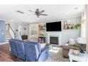 Well-lit living room with a fireplace, a ceiling fan, and adjacent stairs leading to the upper level at 1826 Towne St, Johns Island, SC 29455