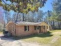 Charming single-story home with brick facade, covered porch, and mature trees in a large yard at 1848 Merrick Dr, Round O, SC 29474