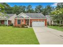 Charming brick home showcasing a well-manicured lawn, lush landscaping, and a two-car garage at 215 Angora Way, Summerville, SC 29485