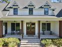 Charming front porch view featuring a brick landing, wooden columns, rocking chairs, and inviting double doors at 4086 Lady Banks Ln, Ravenel, SC 29470