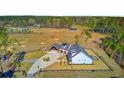 Aerial view of a sprawling, modern farmhouse with a fenced yard and multiple outbuildings at 614 Cummings Chapel Rd, Ridgeville, SC 29472