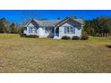 Beautiful white home with blue shutters set on a vast lawn, perfect for outdoor activities at 8524 Cane Branch Rd, Ruffin, SC 29475