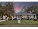 Charming brick home at twilight with lush front lawn, white trim, and window shutters at 105 Chadwick Dr, Charleston, SC 29407