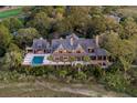 Aerial view of a spacious home featuring a pool, outdoor dining area, and luxurious deck space nestled amongst palm trees at 108 Salthouse Ln, Kiawah Island, SC 29455