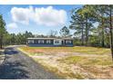 Charming exterior view of a single-story home with a gravel driveway surrounded by lush greenery at 1360 Burr Hill Rd, Cottageville, SC 29435