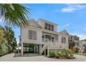Charming two-story beach house with a covered parking area, white trim, and a well-kept front yard landscape at 1702 Palmetto Blvd, Edisto Island, SC 29438